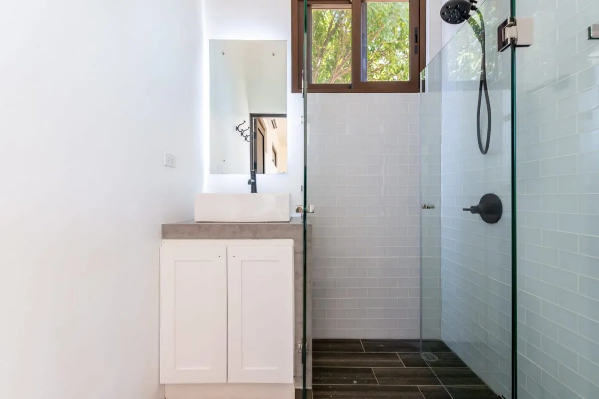 A bright bathroom with a vanity beside a glass-enclosed shower.