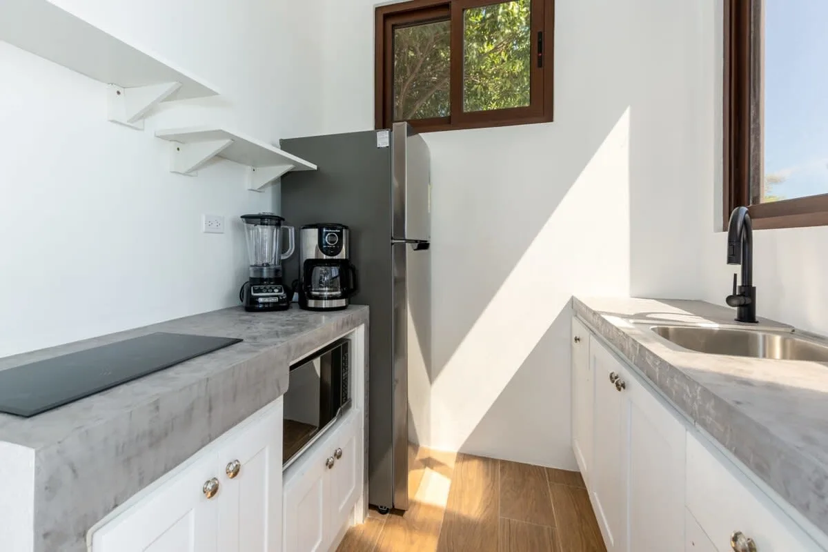A bright kitchen with counters, a refrigerator, and small appliances.