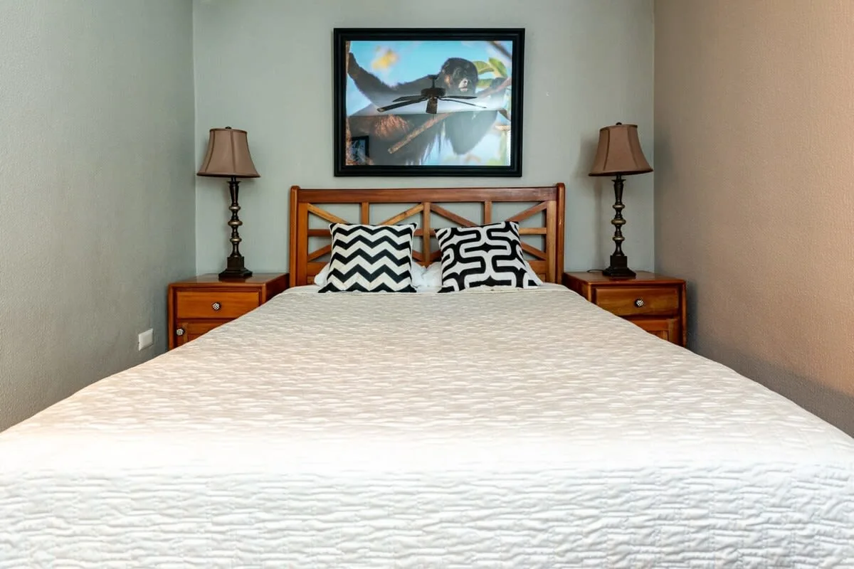 A bedroom with a wooden bed, patterned pillows, and framed artwork above the headboard.
