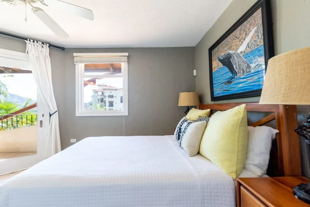A bedroom with a neatly made bed and a large framed picture above it.