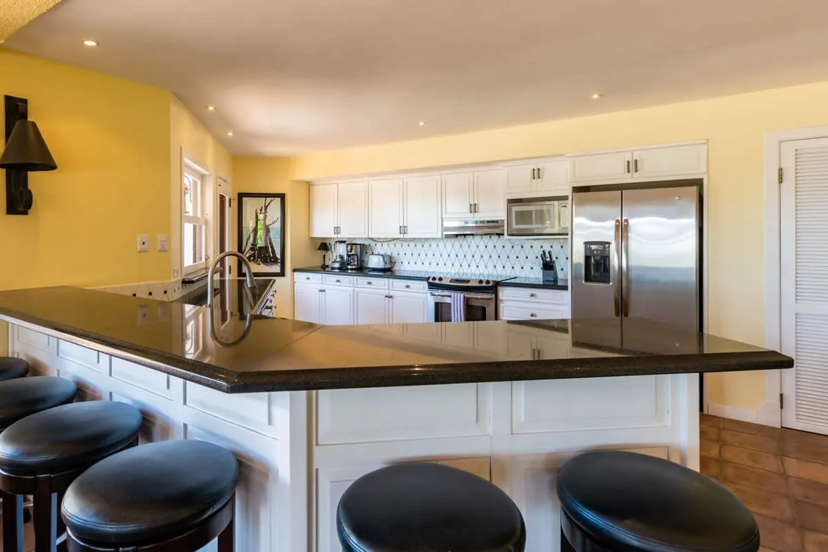 A bright kitchen with white cabinets, stainless steel appliances, and a large island.