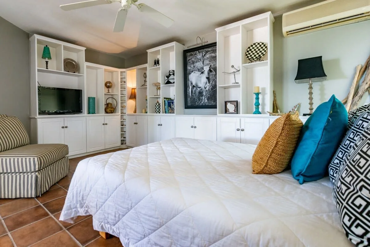A bedroom with a large bed, built-in shelving, and a ceiling fan.