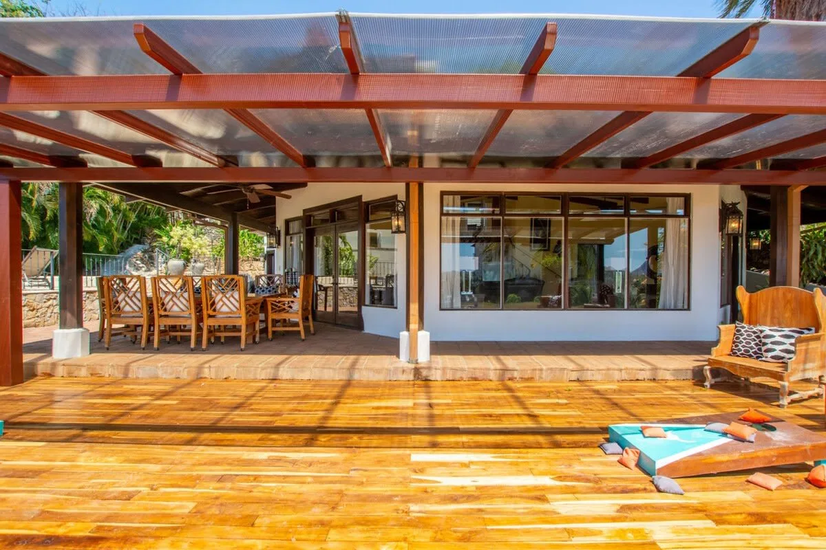 A covered wooden deck with outdoor seating and large glass doors.