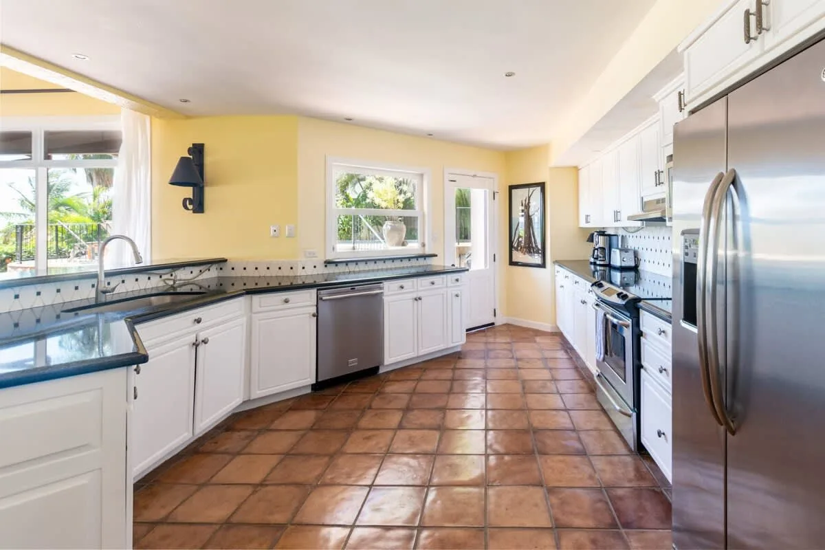 A bright kitchen with white cabinets, tiled counters, and stainless steel appliances.