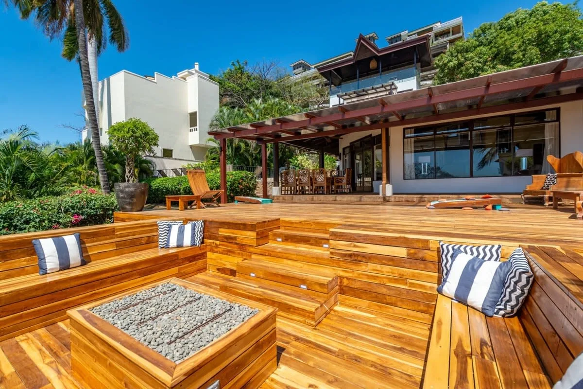 A wooden outdoor deck with built-in seating and a covered patio beside the building.