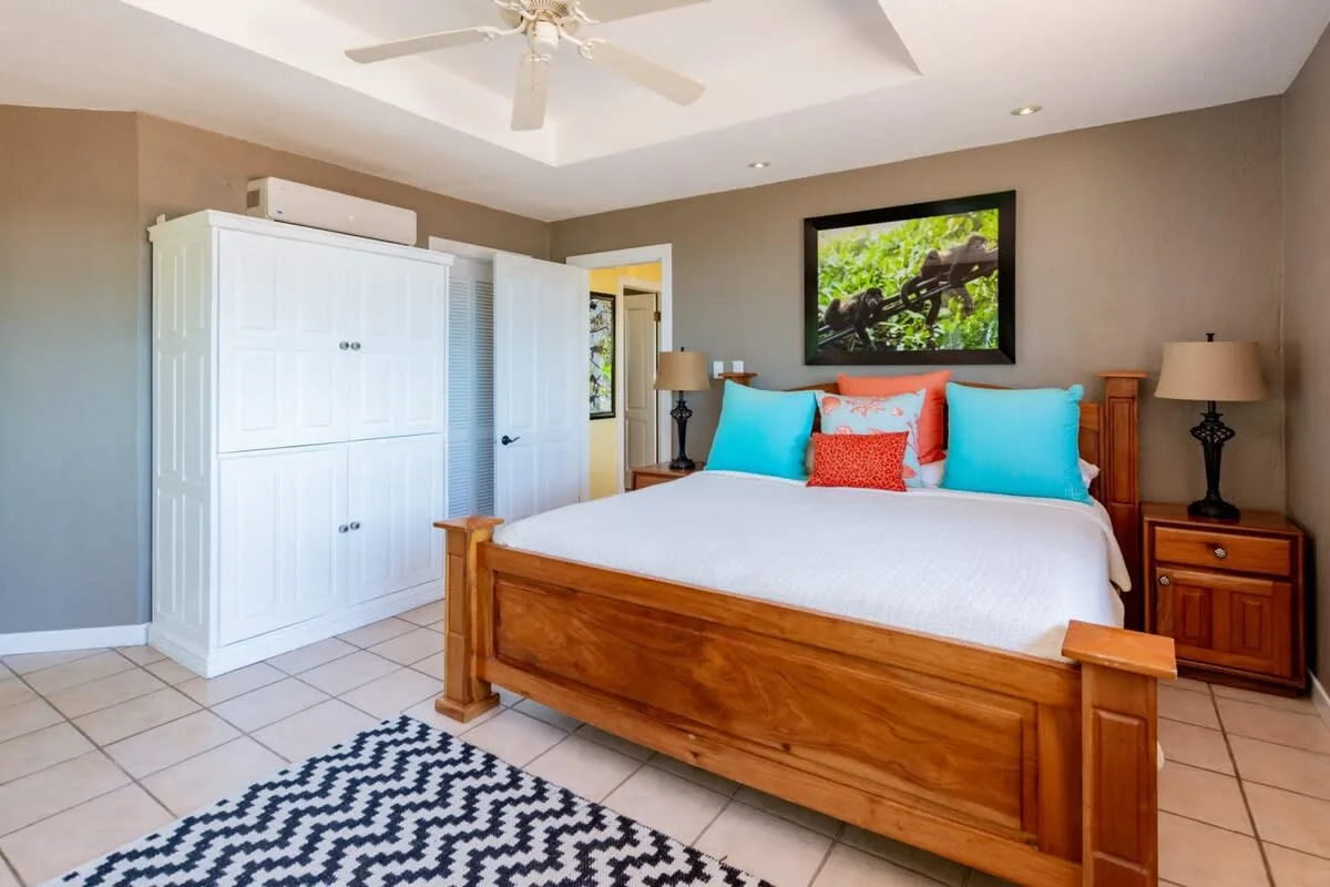 A bedroom with a wooden bed, colorful pillows, and a large white wardrobe.