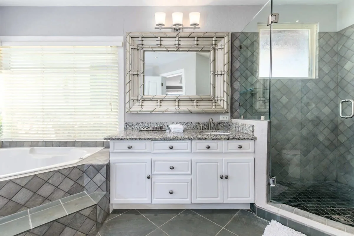 A bathroom with a white vanity, bathtub, and glass shower.