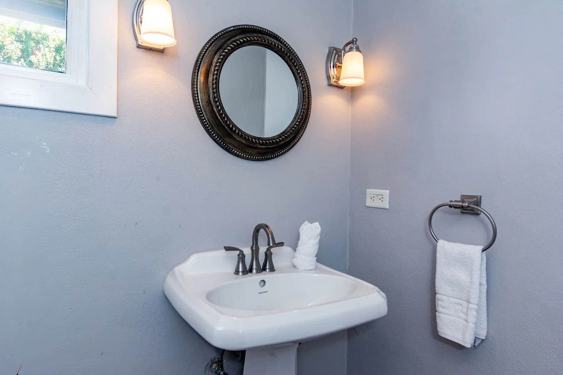 A bathroom vanity with a sink, mirror, and wall-mounted lights.