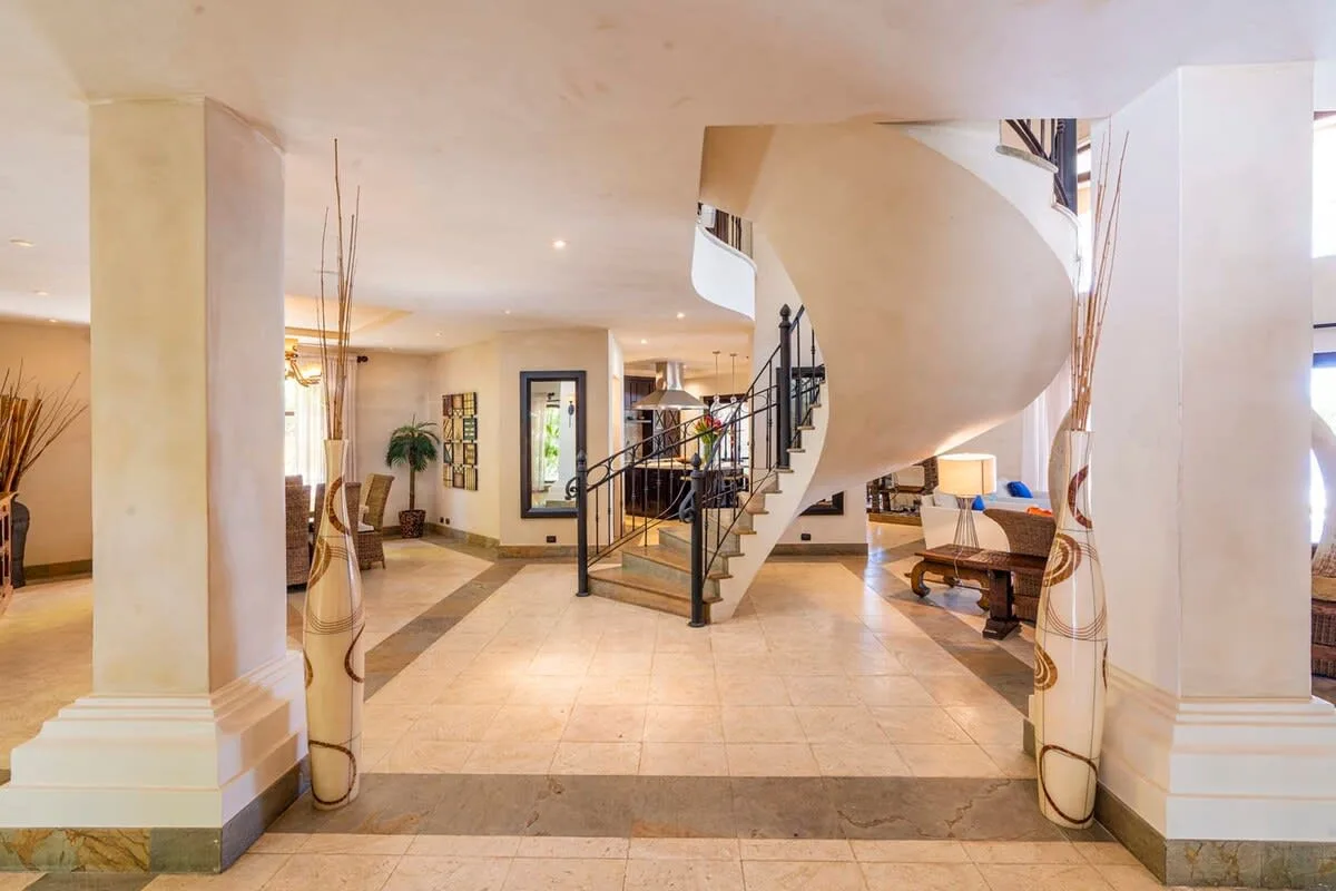 A spacious interior foyer with a curved staircase and tiled floor.