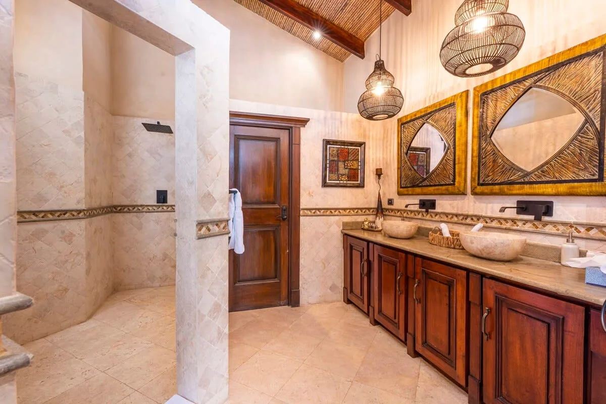 A bathroom with a walk-in shower, wooden vanity, and framed wall art.