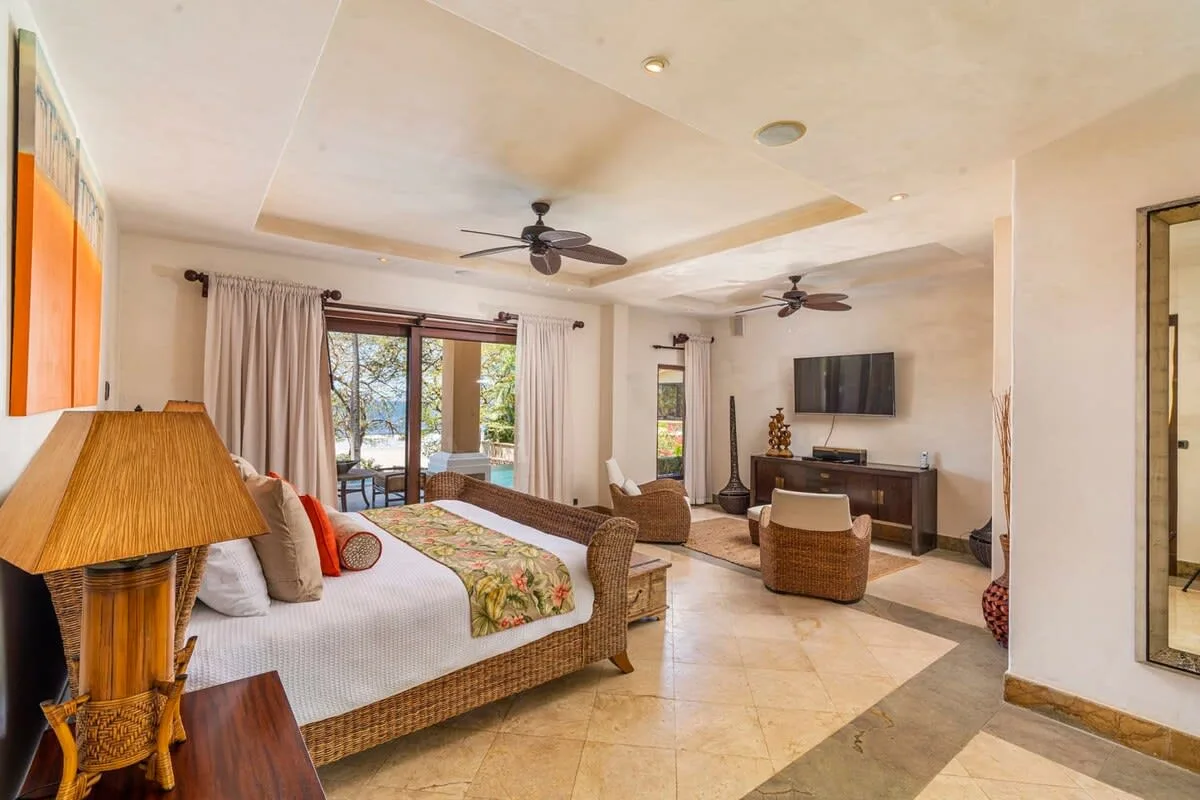 A bright bedroom and sitting area with a bed and television.