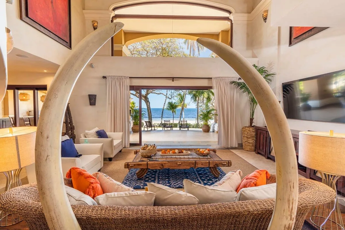 An open living room with seating arranged around a low table, facing a view of the sea.