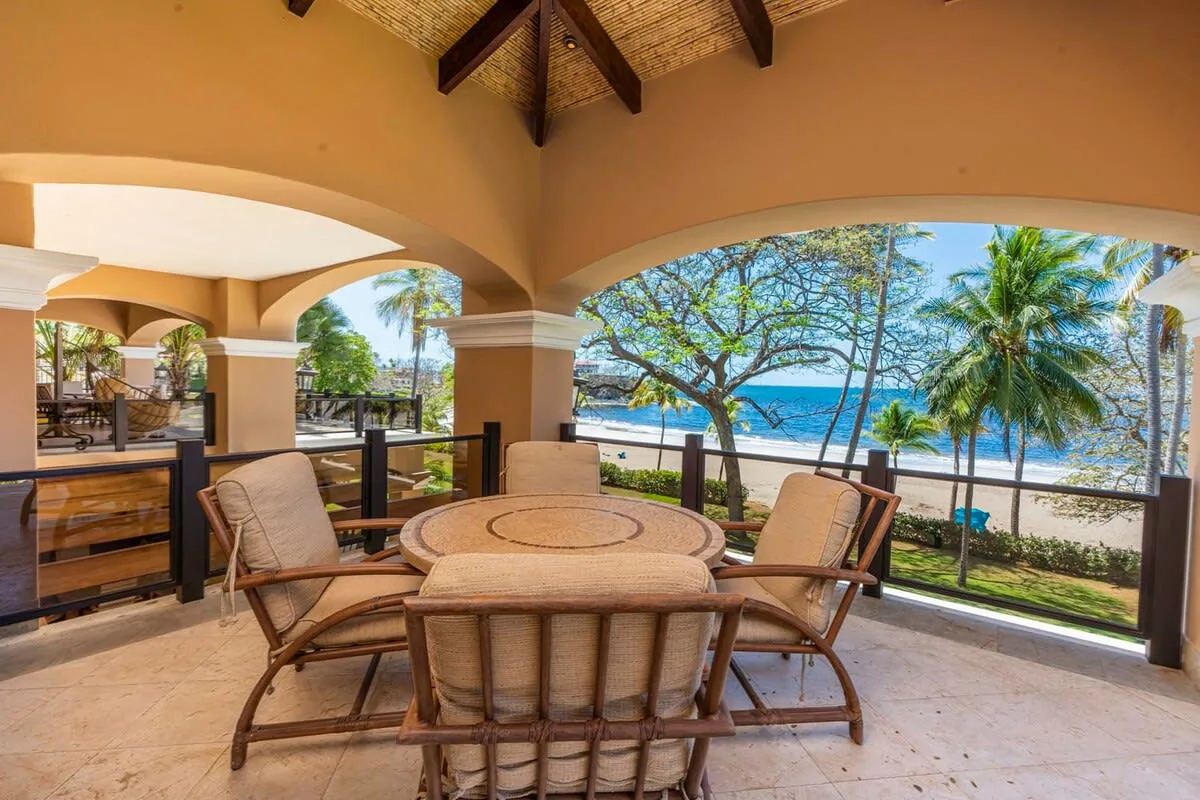 A covered outdoor dining area opens onto a garden and ocean view.