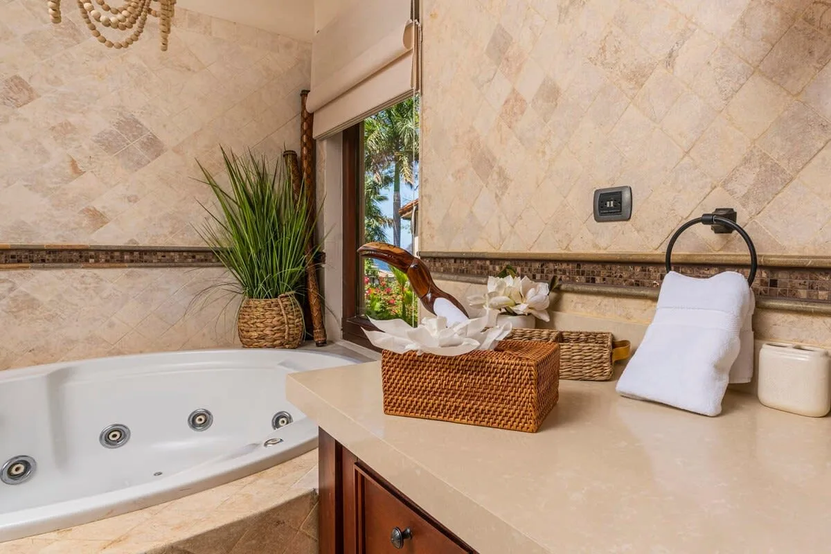 A tiled bathroom with a bathtub, a countertop, and a potted plant.
