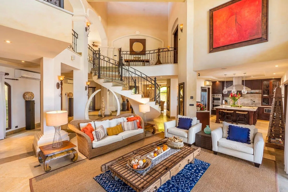 A spacious living room with seating, a coffee table, and a curved staircase.