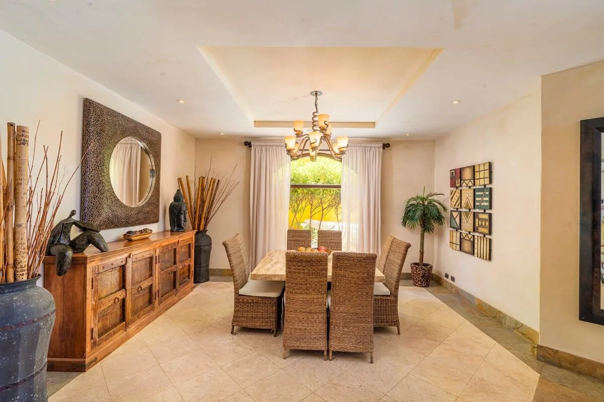 A dining room with a table and woven seating beneath a chandelier.
