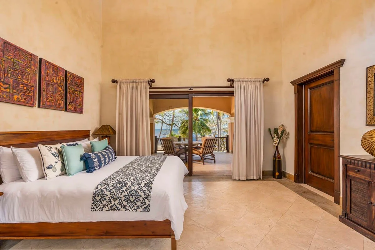 A bedroom with a bed facing sliding glass doors that open onto a patio.