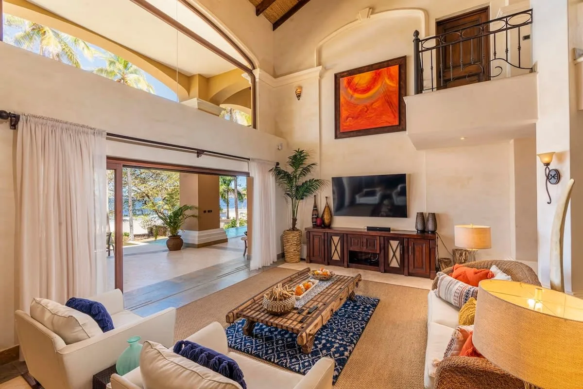 A spacious living room with seating, a coffee table, and a wall-mounted television.