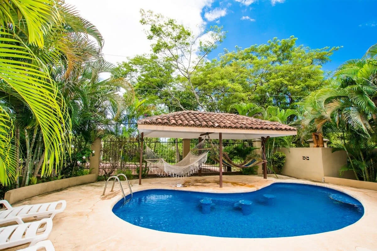 Shared amenity: An outdoor pool sits beside a covered hammock area, surrounded by tropical greenery.