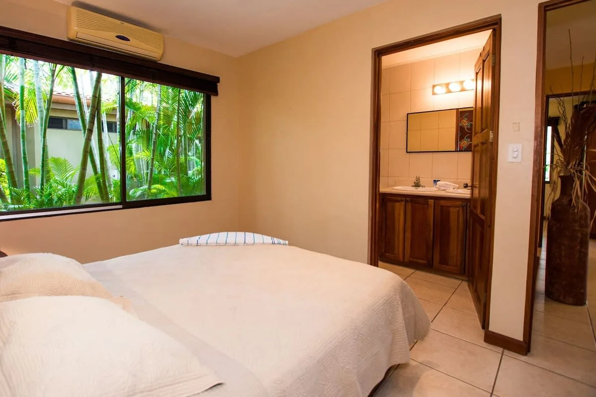 A bedroom with a neatly made bed beside a large window.