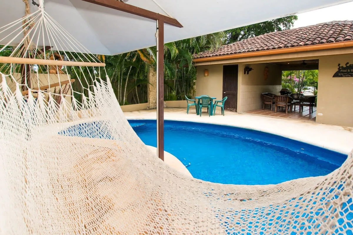 Shared amenity: Outdoor poolside scene with a hammock beneath a shaded canopy.