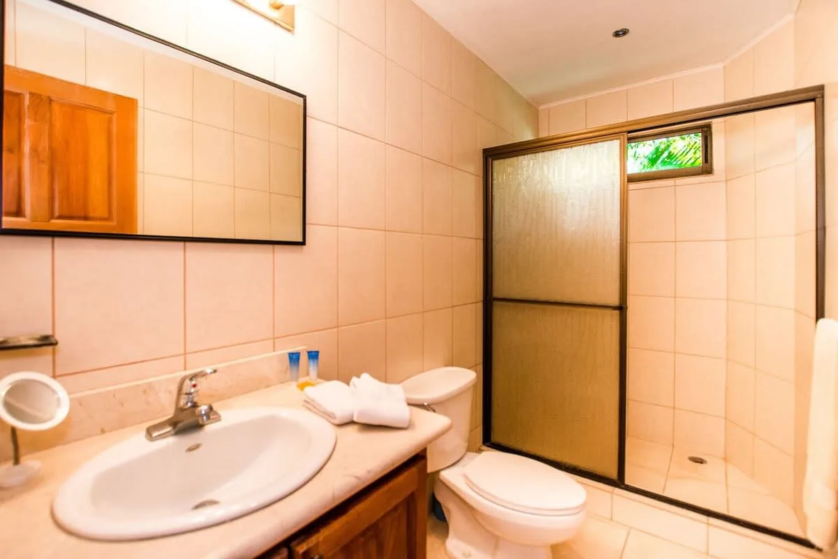 A tiled bathroom with a sink, toilet, and glass shower enclosure.