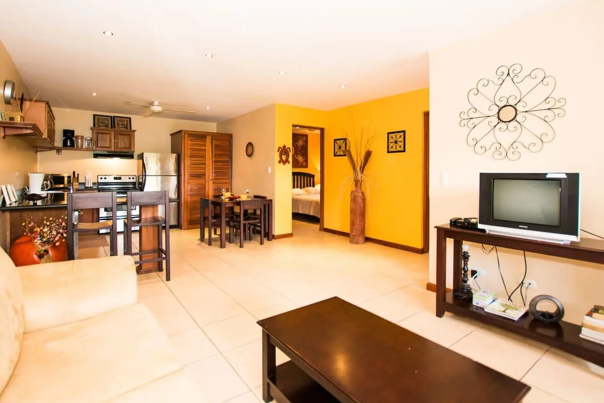 An open living area with a dining table, kitchen, and television.