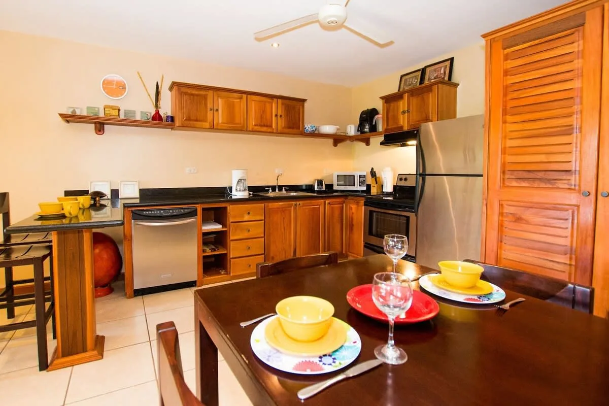 A kitchen and dining area with wooden cabinets and a table set with dishes.