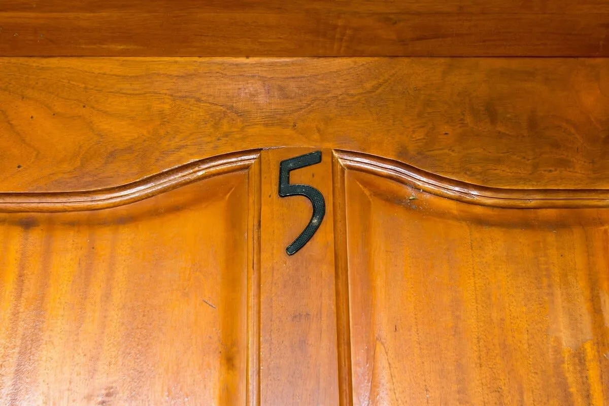A wooden door with a dark number five mounted near the center.