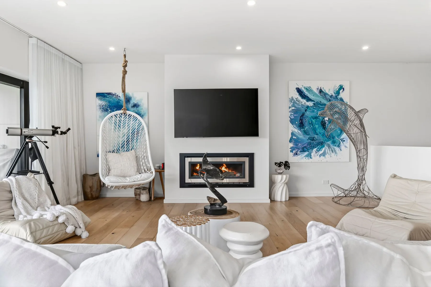 Una sala luminosa con un televisor montado en la pared y una chimenea.