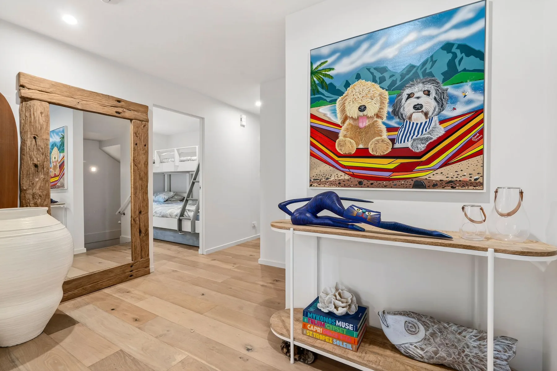 Una luminosa zona de dormitorio con un espejo de marco de madera y arte colorido en la pared.