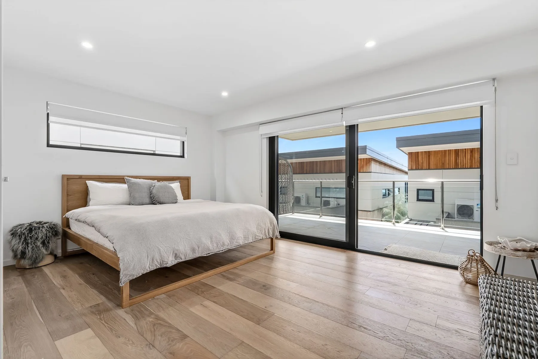 Un dormitorio luminoso con una cama de madera y grandes puertas corredizas de vidrio.