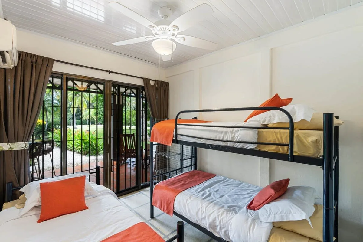 Un dormitorio con literas junto a puertas de vidrio que dan a un jardín.