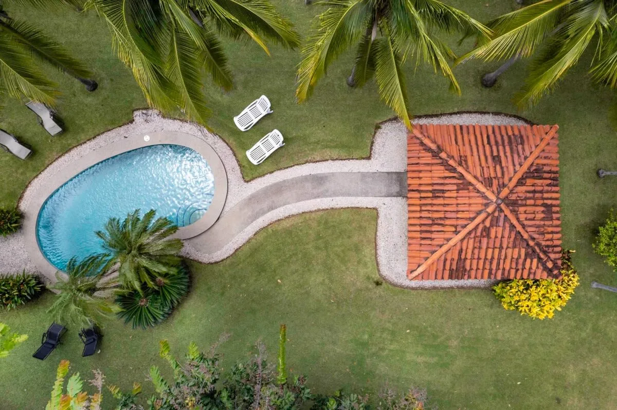 Vista aérea de una piscina curva junto a un edificio con techo de tejas.