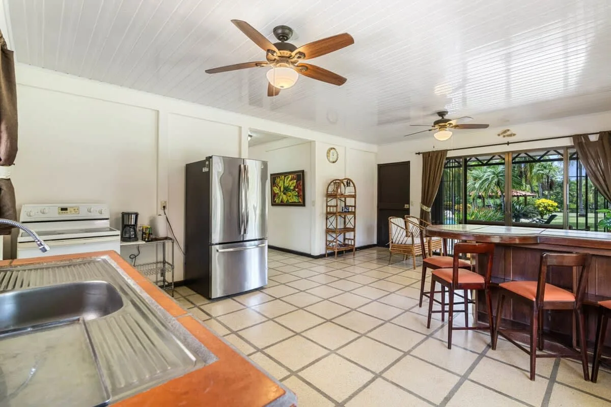 Una cocina luminosa con refrigerador de acero inoxidable, fregadero y barra de comedor.