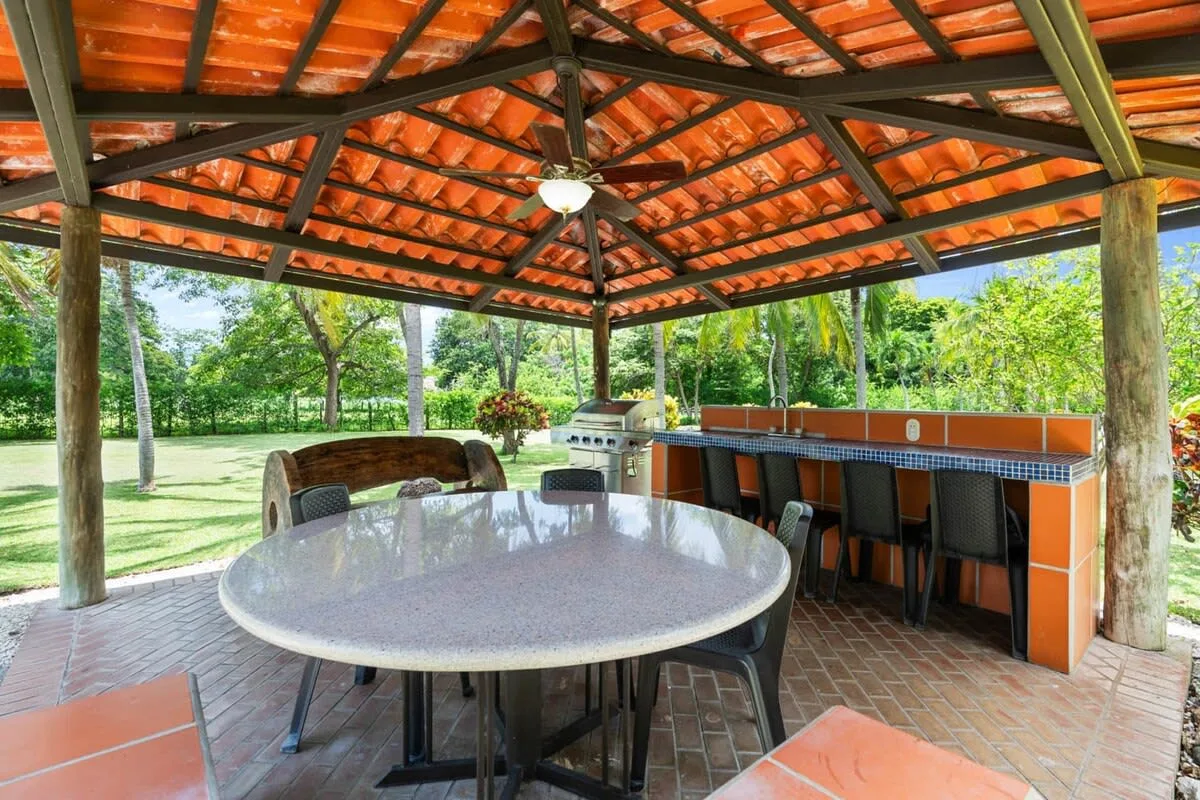 Comedor exterior cubierto con una mesa y una barra revestida de azulejos.