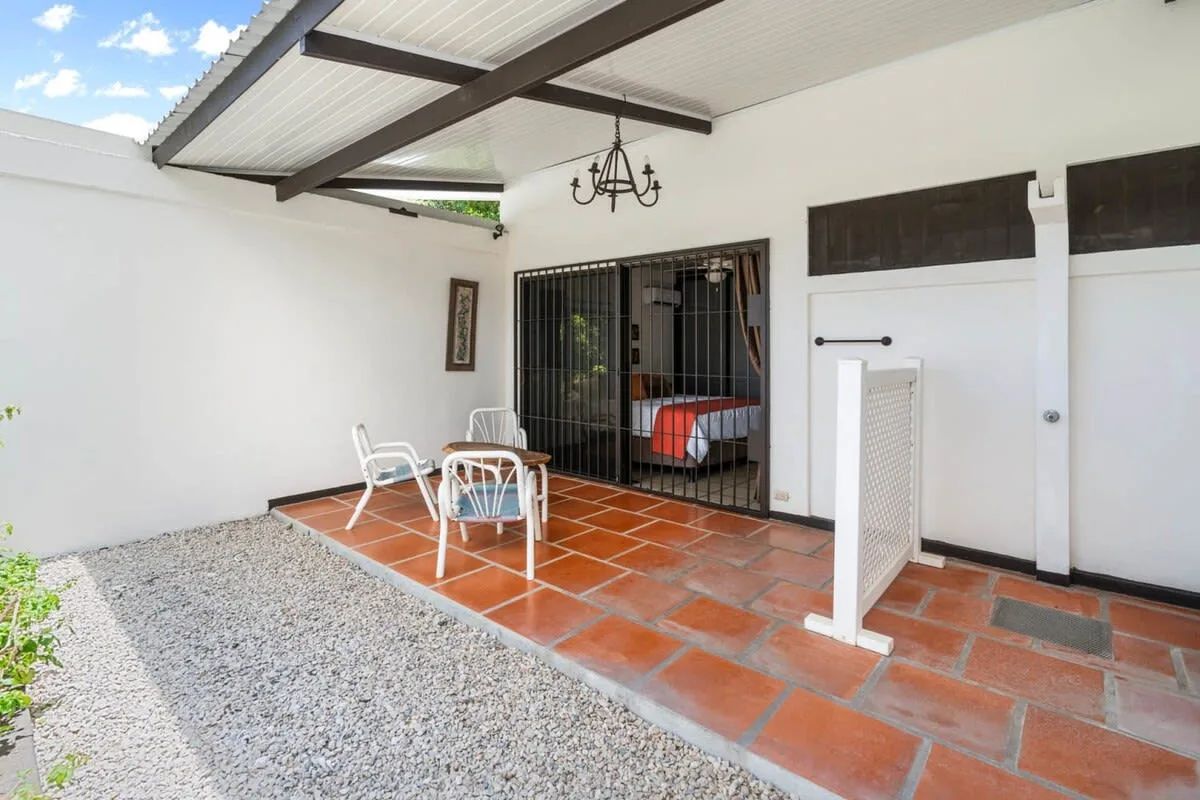 Un patio cubierto con suelo de baldosas y una pequeña zona para sentarse.