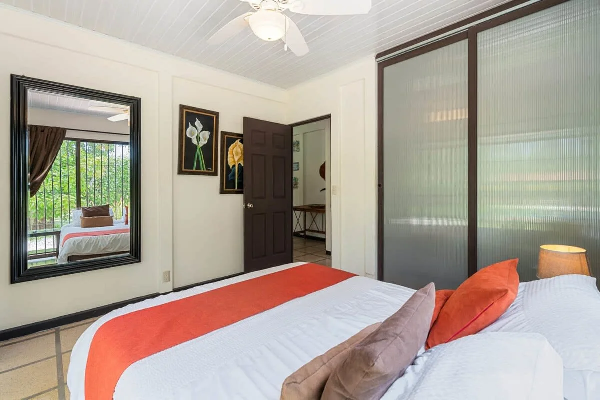 Un dormitorio con una cama, almohadas de colores y una puerta corrediza de clóset.