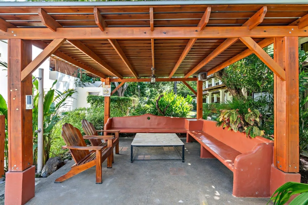 Shared amenity: A covered outdoor seating area with wooden benches and surrounding plants.