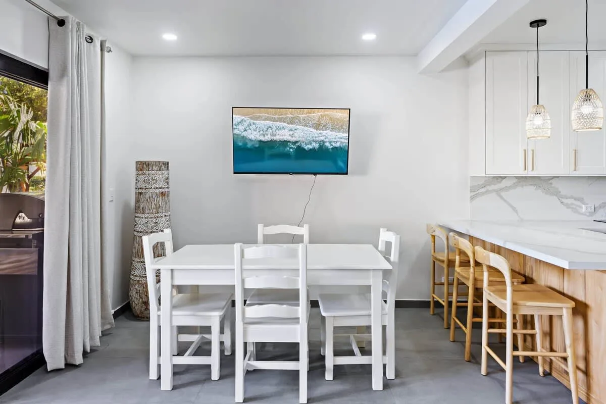 A bright dining area with a white table beside a kitchen counter.
