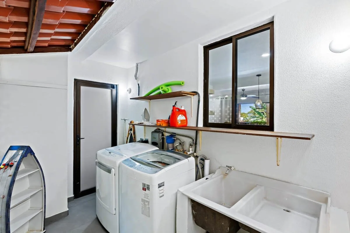 A laundry area with washing machines, a utility sink, and storage shelves.