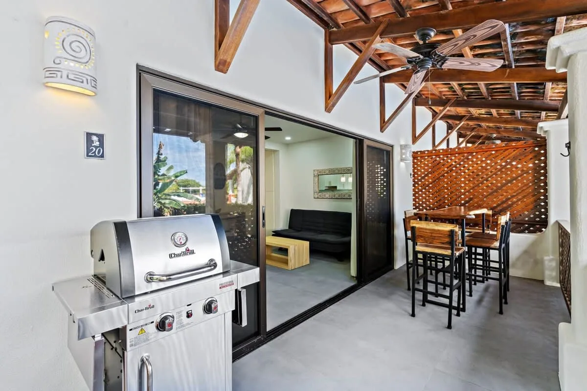 A covered patio with a grill, dining table, and seating visible through sliding glass doors.