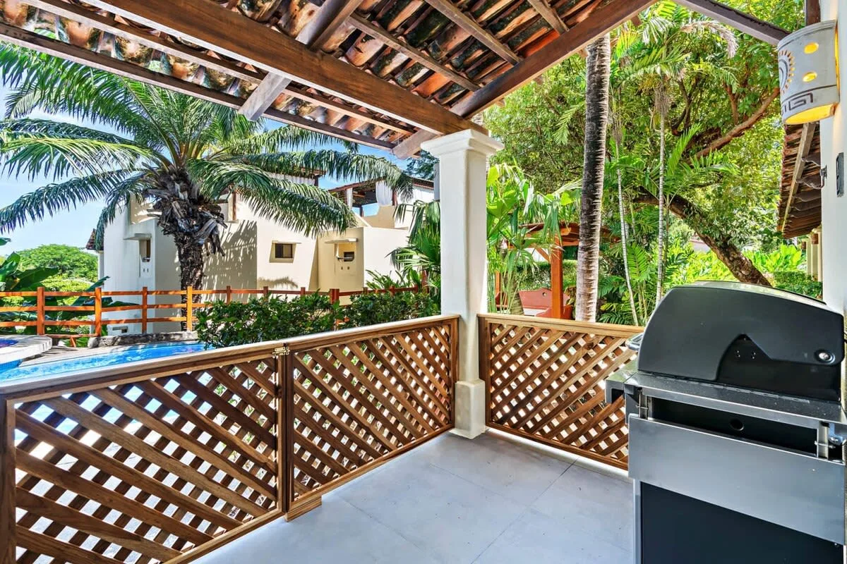 A covered outdoor patio with a built-in grill and wooden lattice railing.