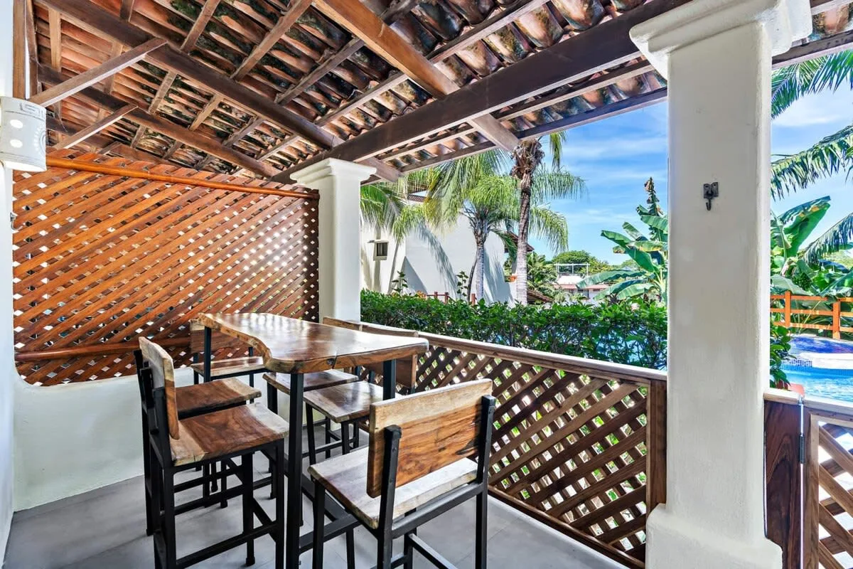 A covered outdoor dining area with a wooden table and seating.