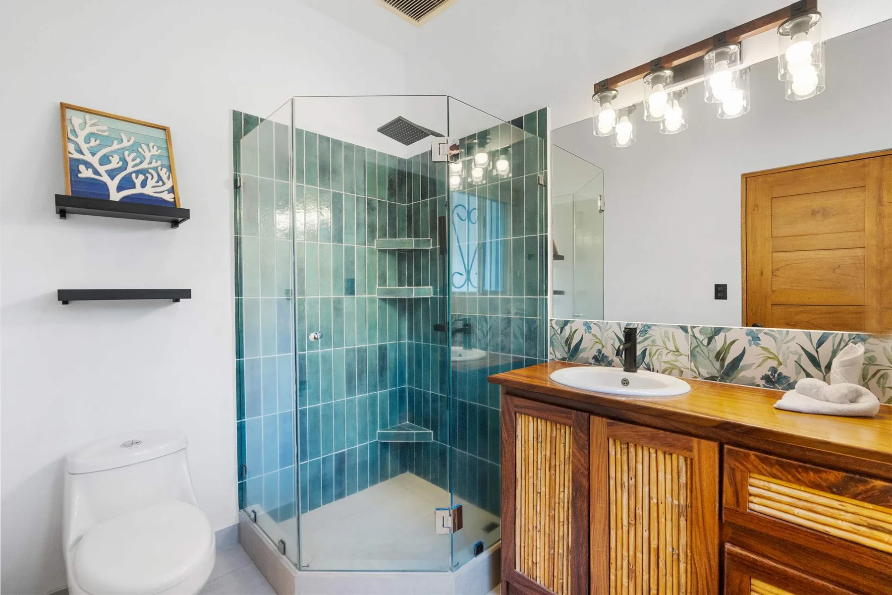 Un baño con ducha de vidrio, lavabo y tocador de madera.
