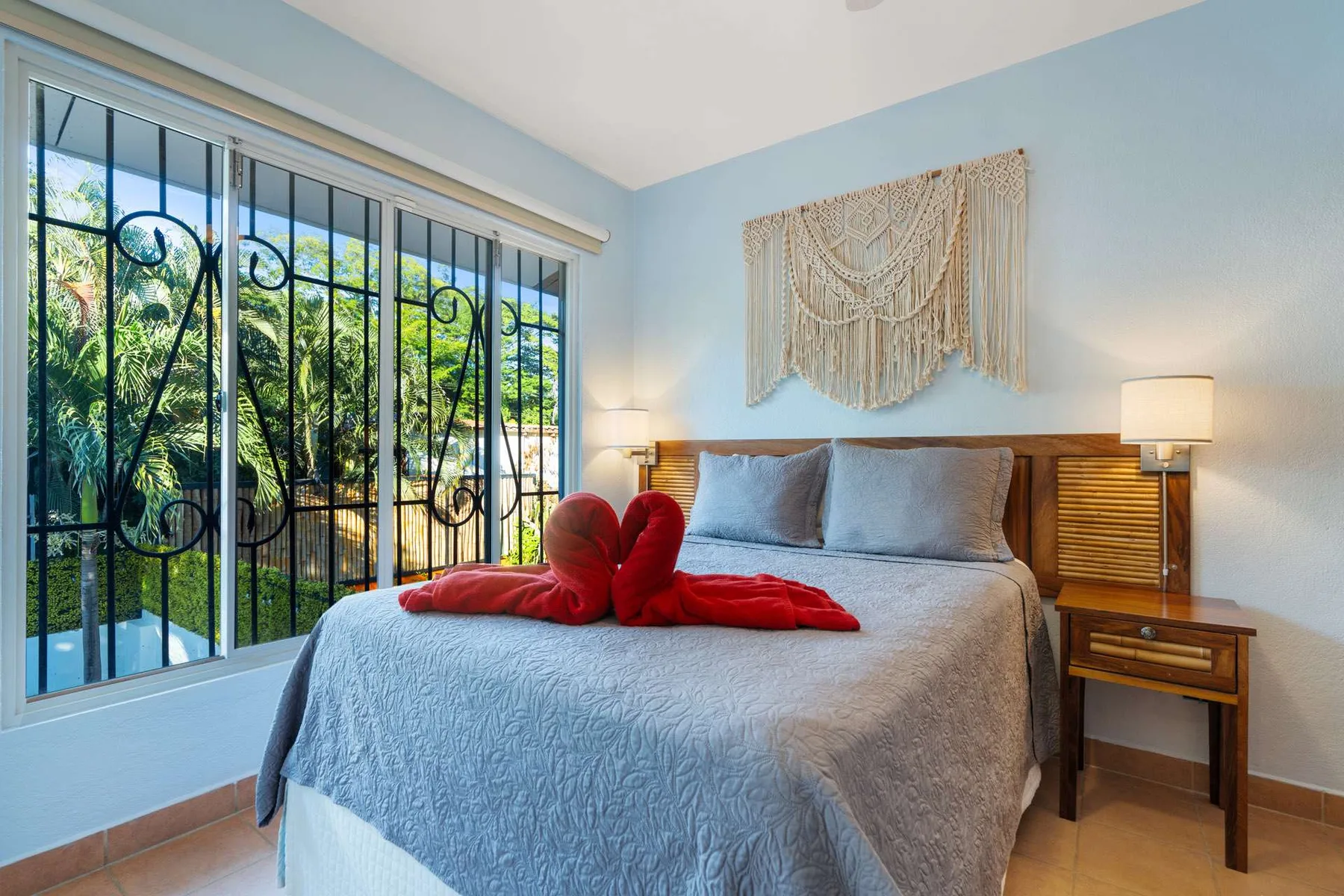 Un dormitorio con una cama bajo un tapiz tejido y una ventana grande.