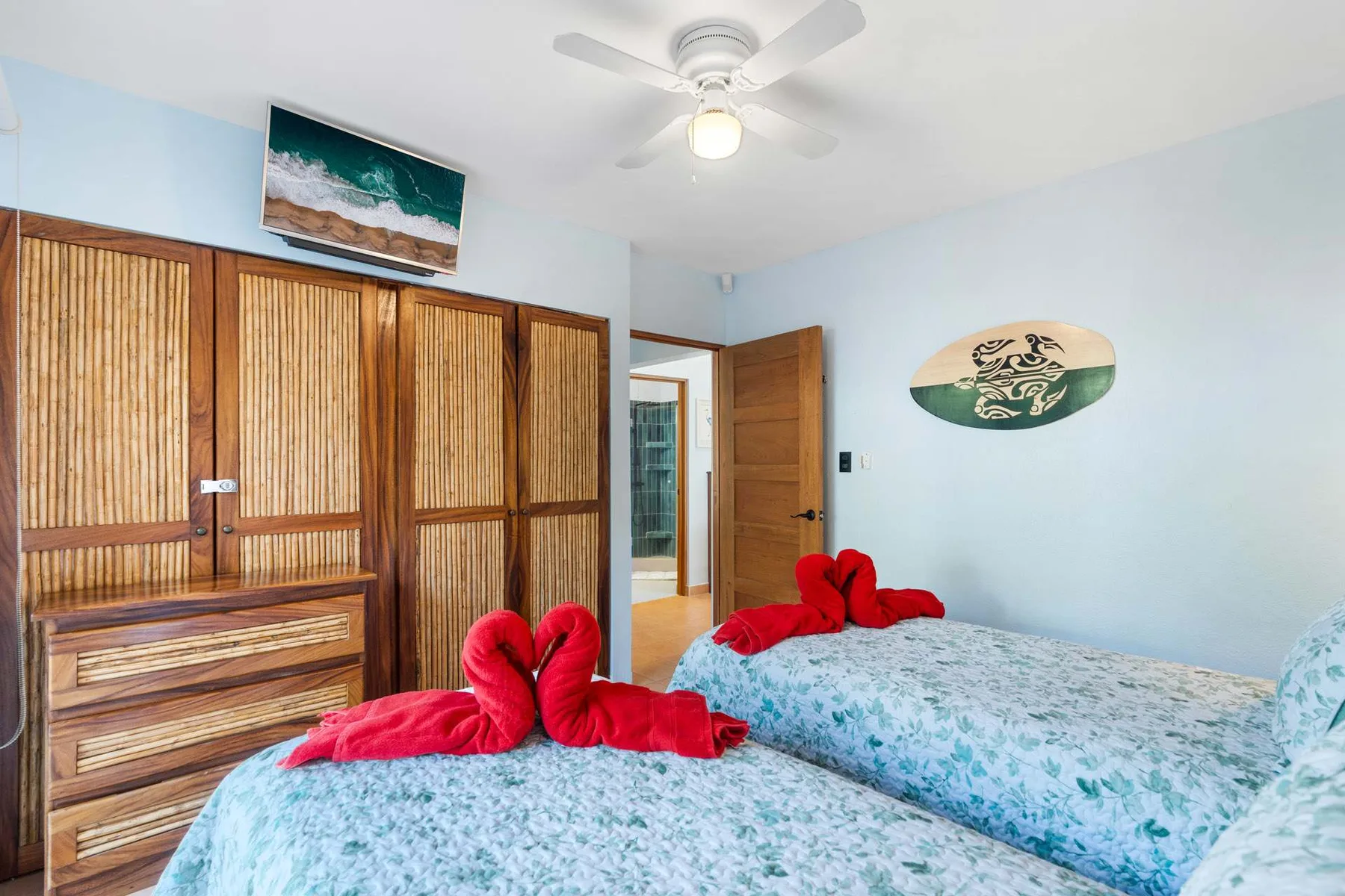 Un dormitorio con dos camas, ropa de cama estampada y puertas de armario de madera.