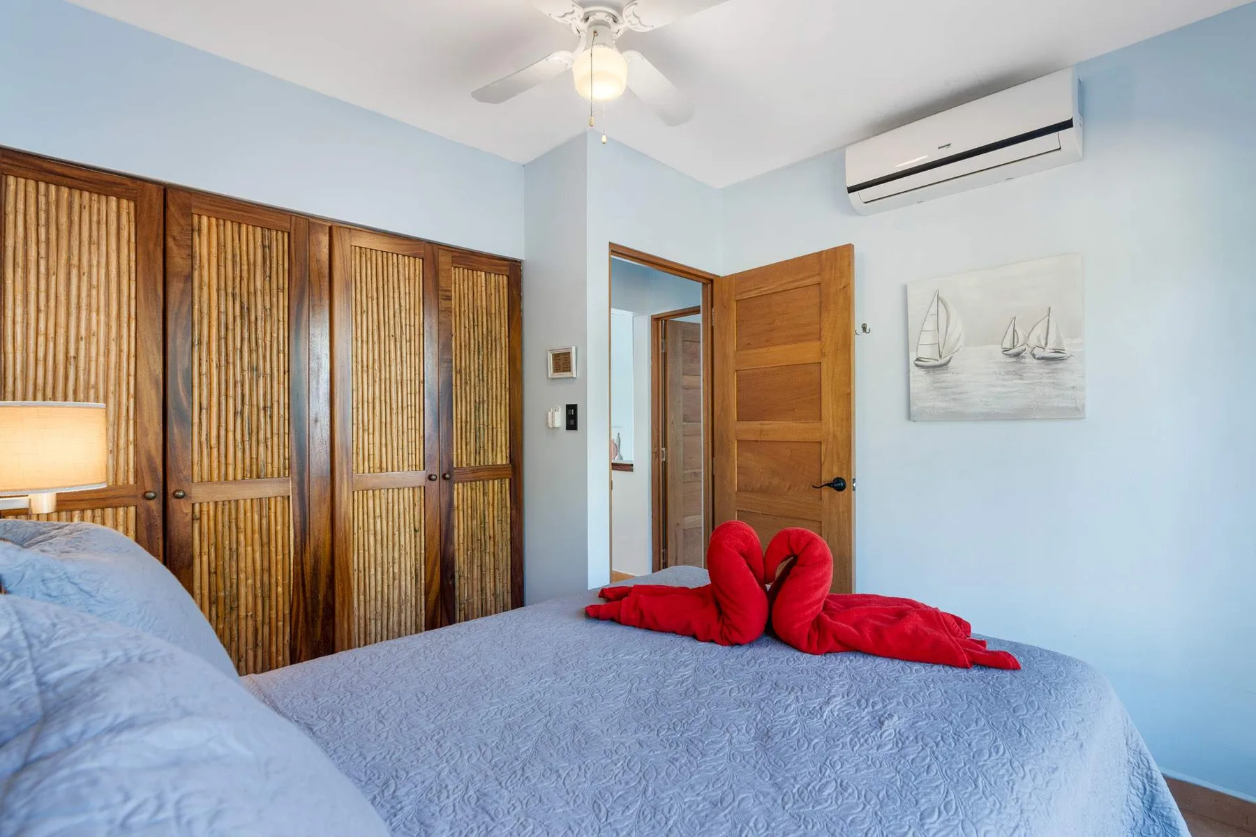 Un dormitorio con una cama, armarios de madera y un ventilador de techo.