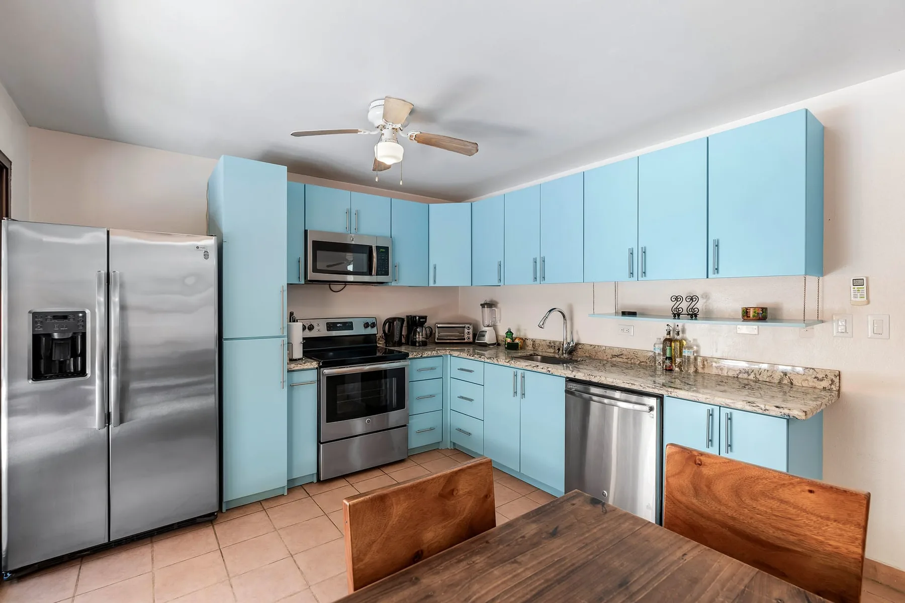 A kitchen with blue cabinets, stainless steel appliances, and a dining table.