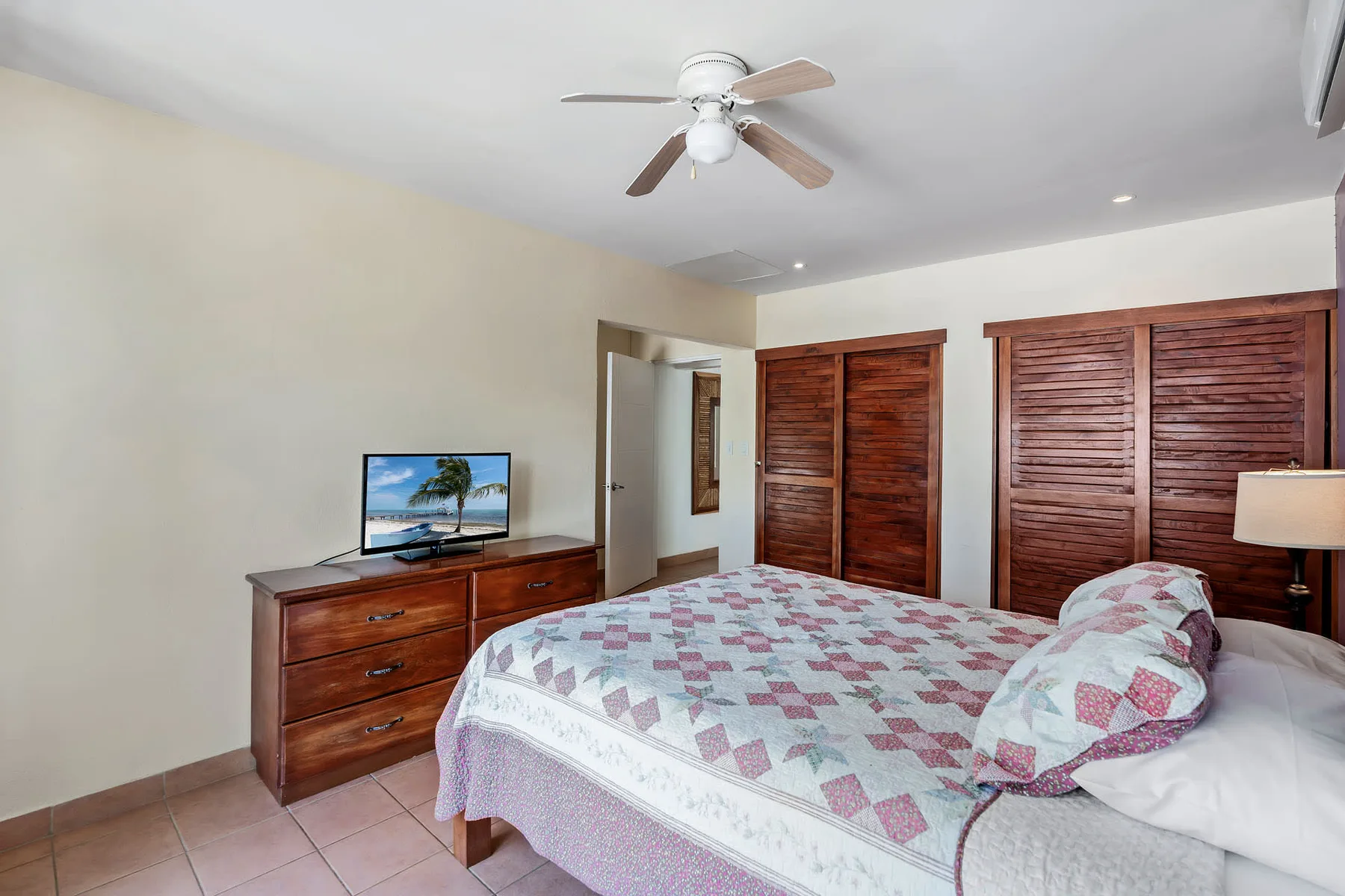 A bedroom with a bed, a dresser, and wooden closet doors.